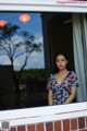 A woman standing in front of a window looking out at the moon.