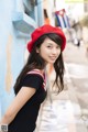 A woman in a red beret leaning against a blue wall.