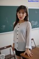 A woman standing in front of a blackboard in a classroom.