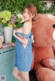 A woman in a blue dress standing next to a teddy bear.