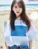 A young woman standing on a beach next to the ocean.