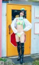 A woman in a bikini and boots standing in front of a yellow door.