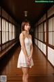 A woman in a white dress standing in a long hallway.