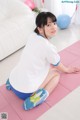 A woman sitting on a pink yoga mat in a living room.