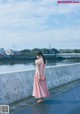 A woman in a pink dress standing on a bridge.