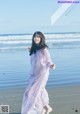 A woman in a long dress running on the beach.