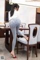 A woman in a white shirt and jeans is sitting at a table.