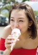 A woman in a red dress eating an ice cream cone.