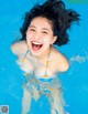 A young girl in a swimming pool with her hair blowing in the wind.