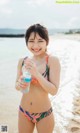 A woman in a bikini holding a bottle of water.