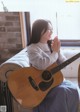 A woman sitting on a couch playing a guitar.