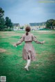 A woman in a trench coat is walking in a field.