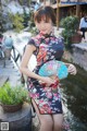 A woman in a black and red dress holding a fan.